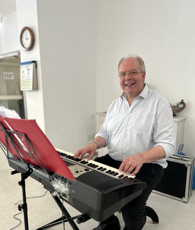 Georg Steffens sitzt am Keyboard und lächelt in die Kamera.