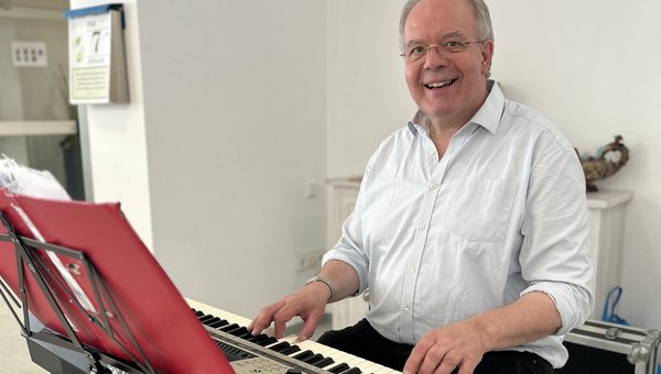 Georg Steffens sitzt am Keyboard und lächelt in die Kamera.